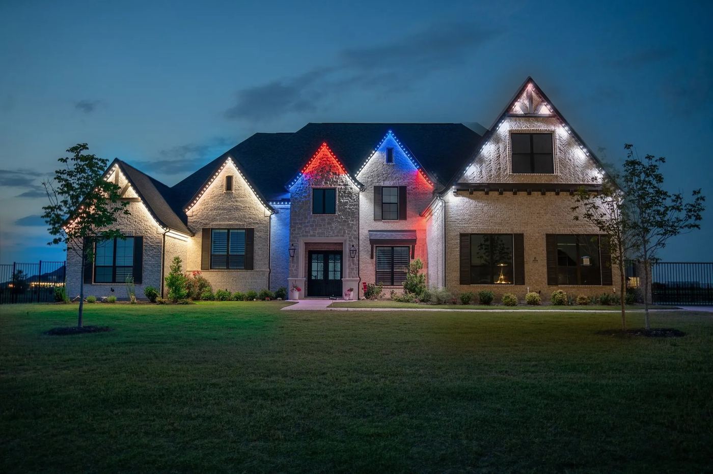 One home showing three permanent lighting looks at once: warm white, red white and blue, and bright white